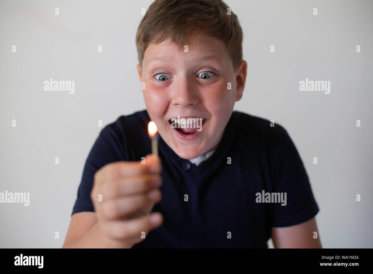 Boy pyromaniac looking to the fire match. Concept of pyromania Stock Photo