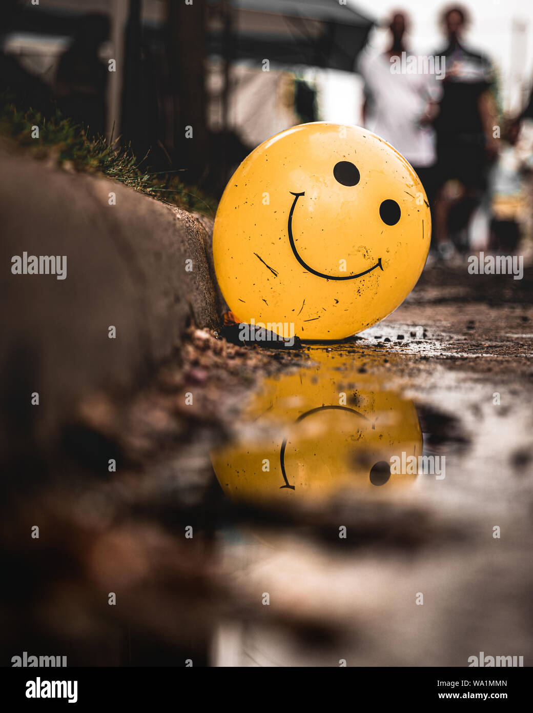 Dirty Smiley Balloon partially being reflected by dirty street water Stock  Photo - Alamy