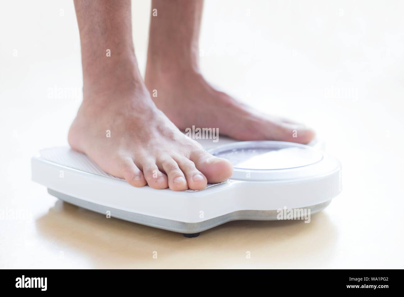 Man standing on weighing scales. Stock Photo