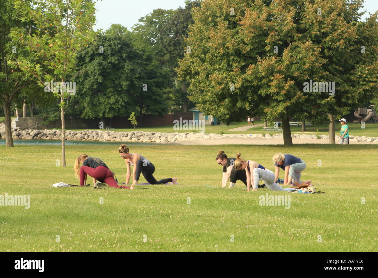 Small yoga class for the community on a warm August morning along the shore of Lake Michigan. Stock Photo