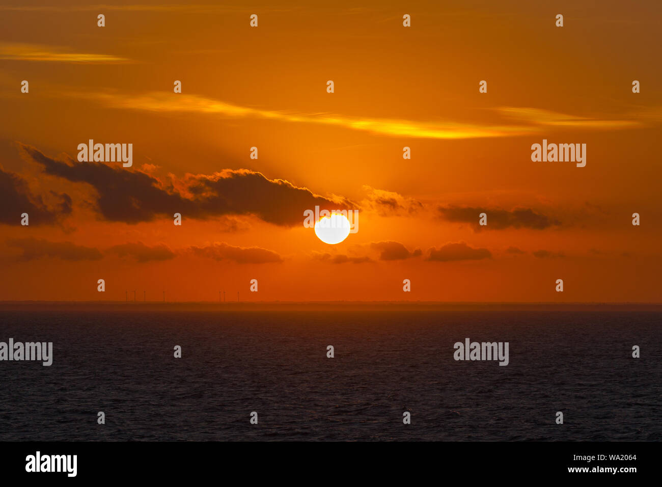 Dreamy sunset on italian coast with orange sky and wind turbines, Puglia, Italy Stock Photo