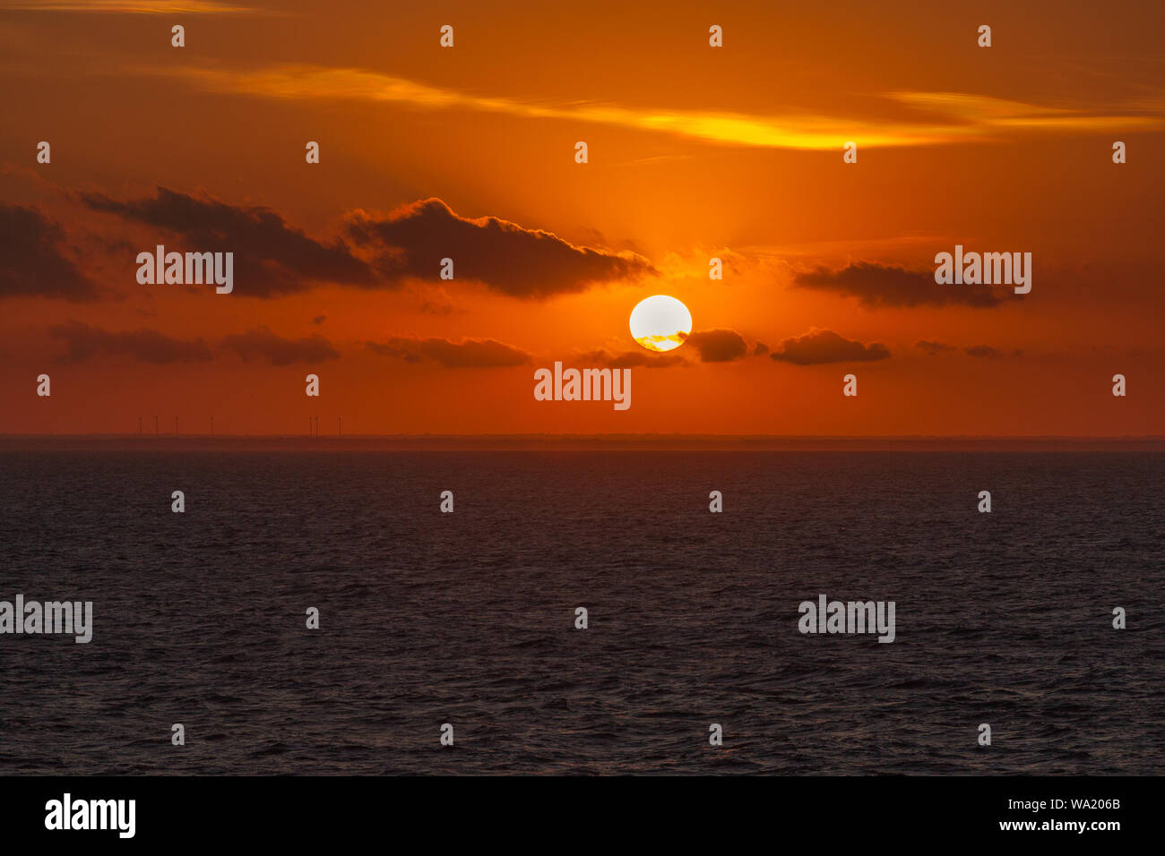 Beautiful sunset on italian coast with orange sky and wind turbines, Puglia, Italy Stock Photo