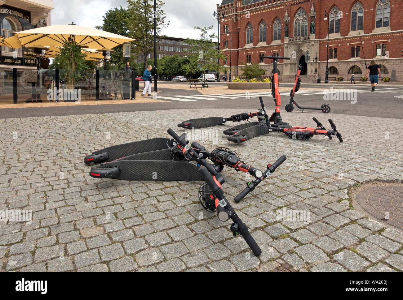 Electric VOI E-scooters thrown in the pedestrian area in front of the city hall at the Harbour Square in Swedish city Helsingborg. Pedestrian hazard. Stock Photo