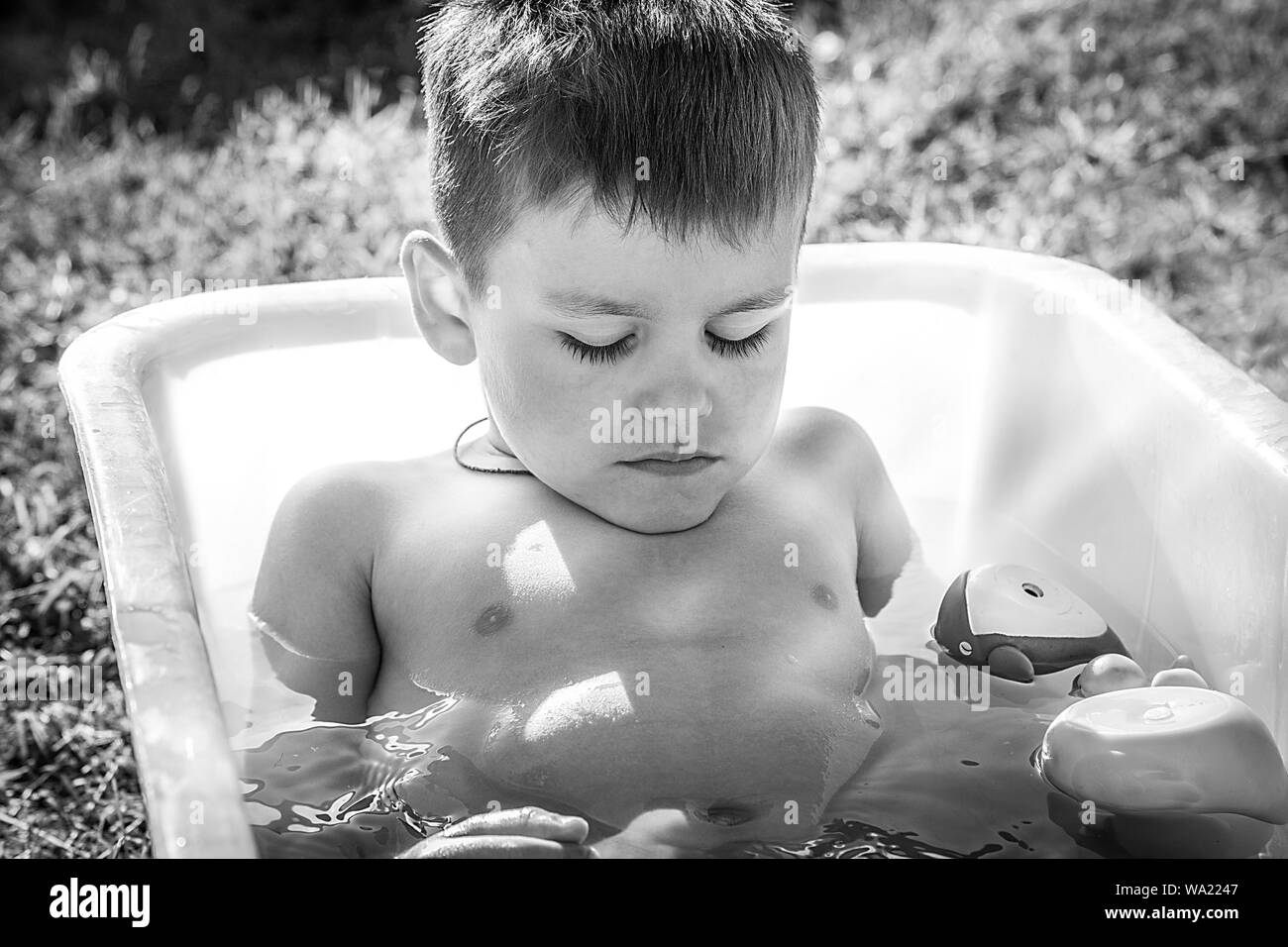 Black and white photo little boy sleeping in a bath black and white