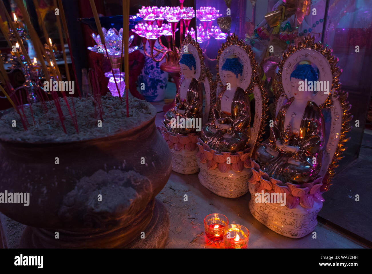 Ho Chi Minh City, Vietnam: obscure temple interior with incense sticks, candles, statues lit with purple lamp light in Tam Son Pagoda, Cho Lon. Stock Photo