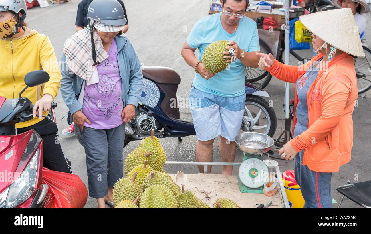 Ho Chi Minh City, Vietnam - May 1, 2019: a man buys a durian at a street vendor's place at a street market adjacent to Cho Lon bus station. Stock Photo