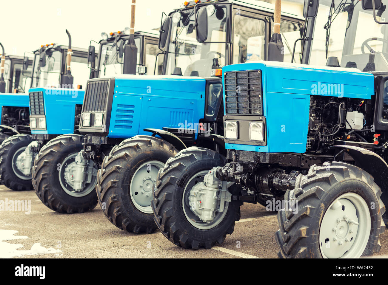 Many different tractors standing in row at agricultural fair for sale
