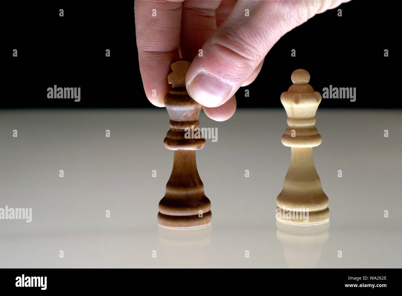 Hand moving a black chess king next to the white queen, as a concept for rivalry, competition, power games. Stock Photo