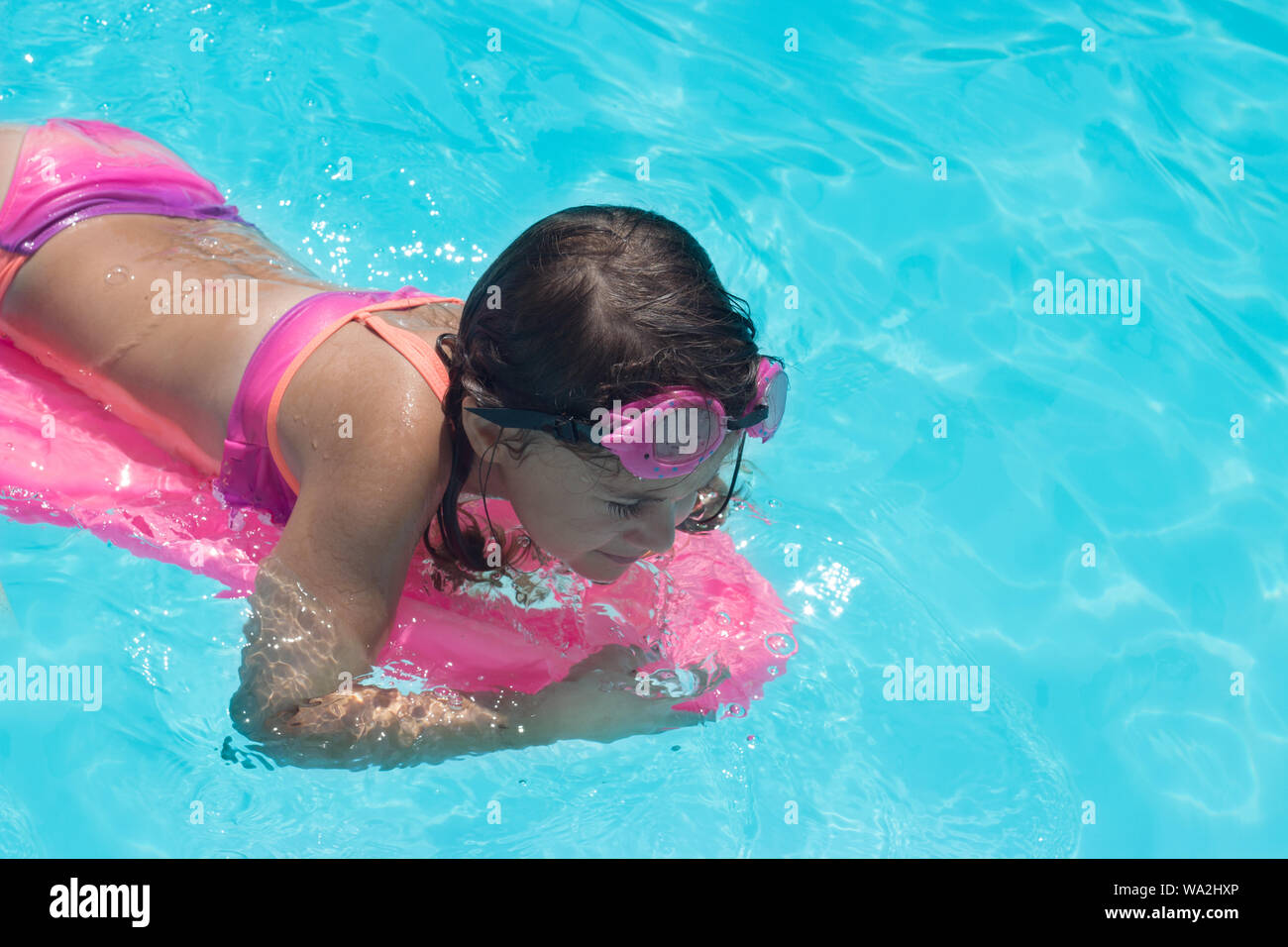 Little girl swims in the pool; summertime background with copy space Stock Photo