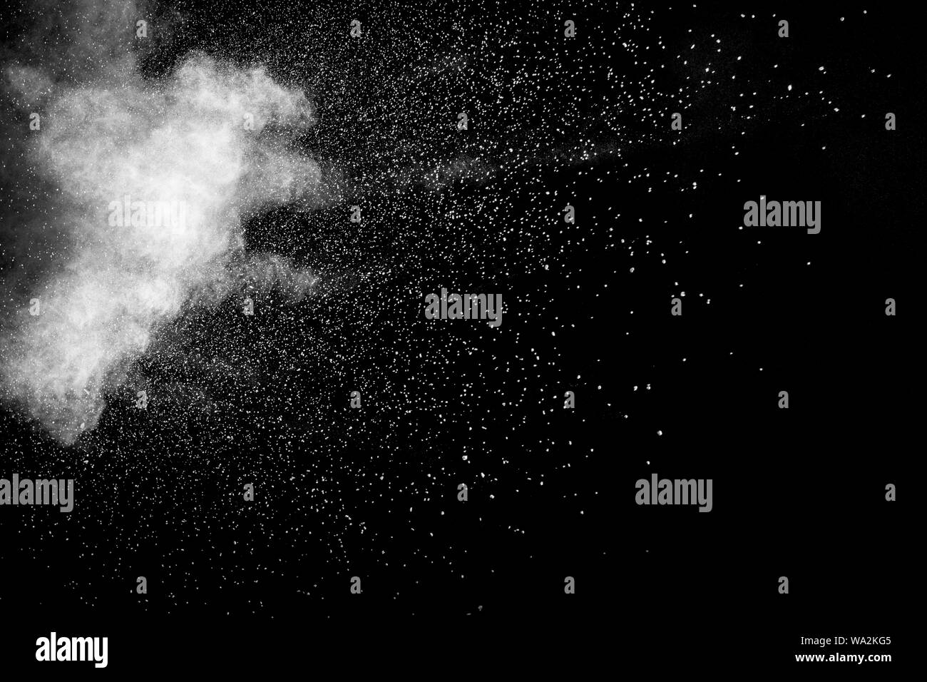 Bizarre forms of white powder explosion cloud against black background.White dust particles splash. Stock Photo