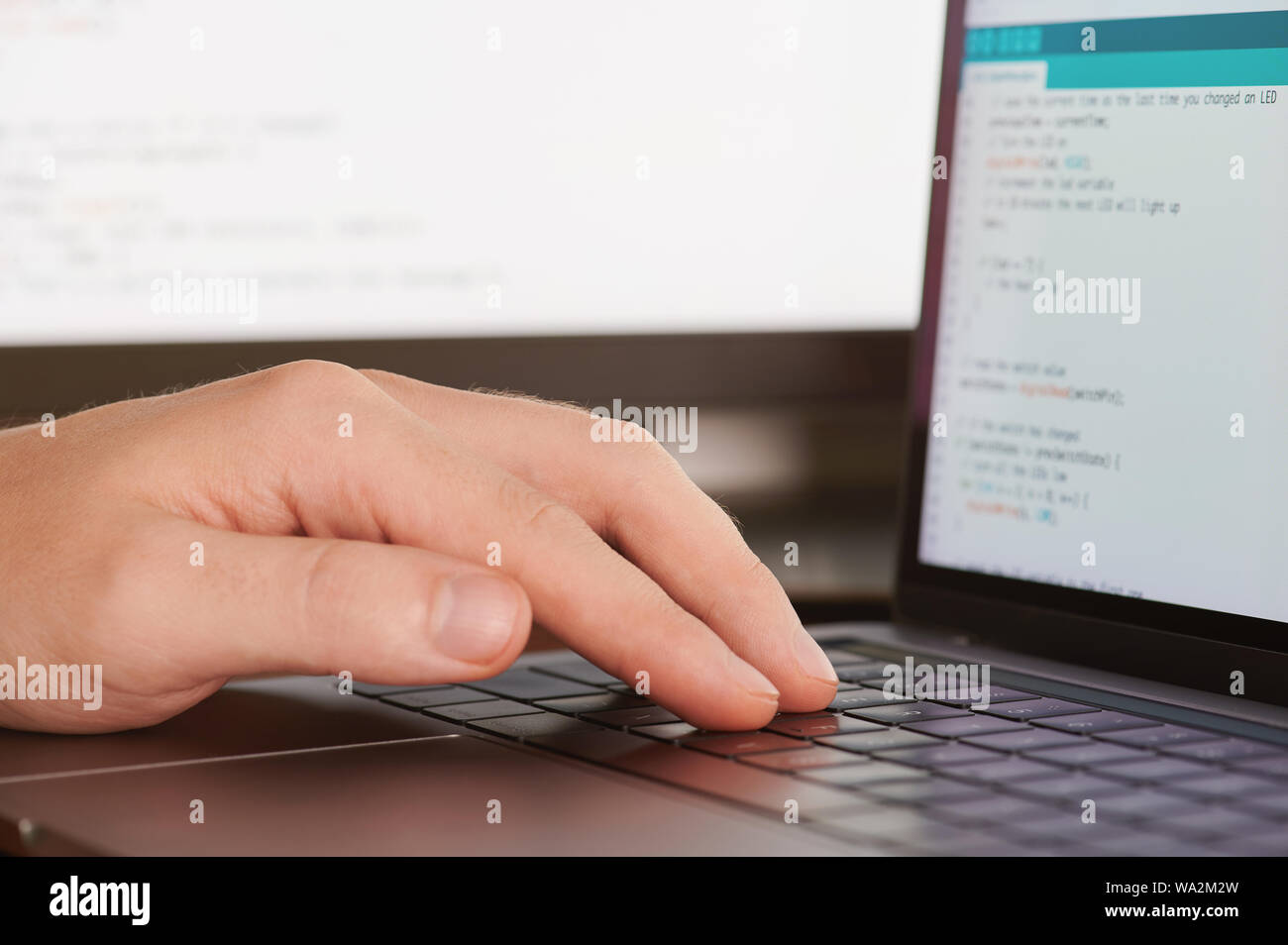 Man typing programming code close up view on blurred screen background Stock Photo