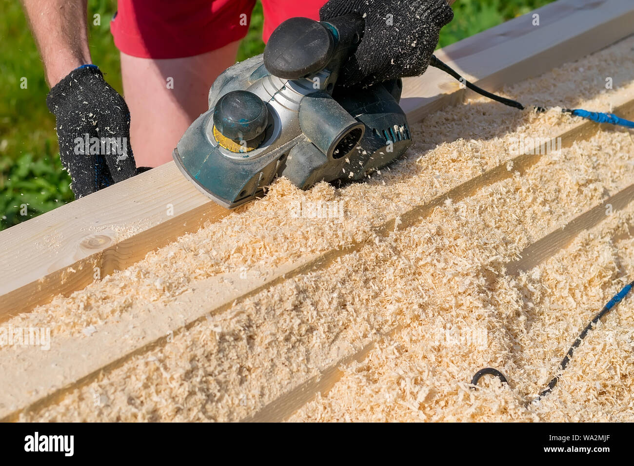 man planing boards with electric tools, chips flying in all directions. Construction, wood
