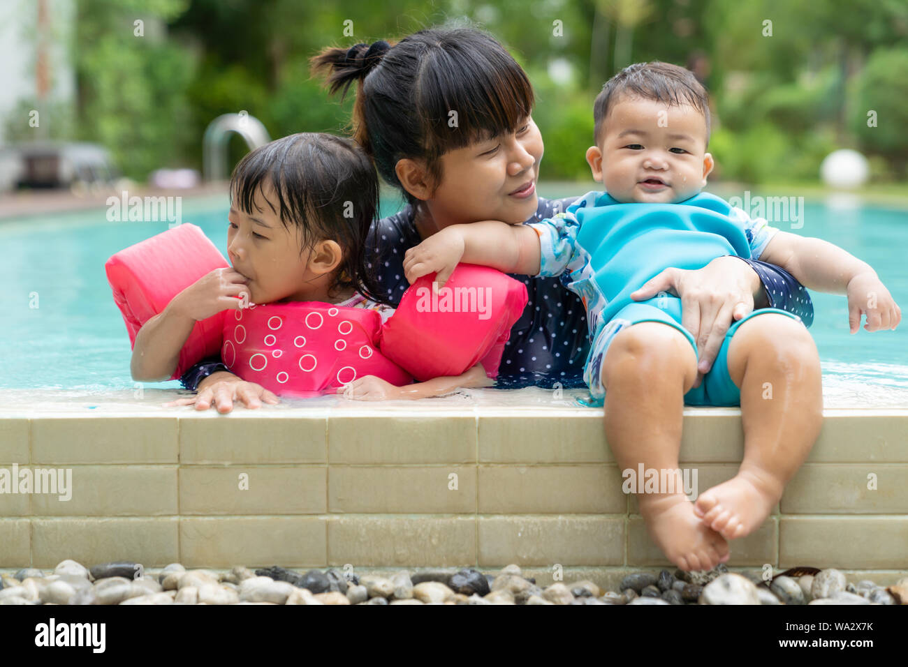 Asian cute little baby girl ans boy swimming from mother take care in pool, family daughter and son, children learning to swim lessons and early devel Stock Photo