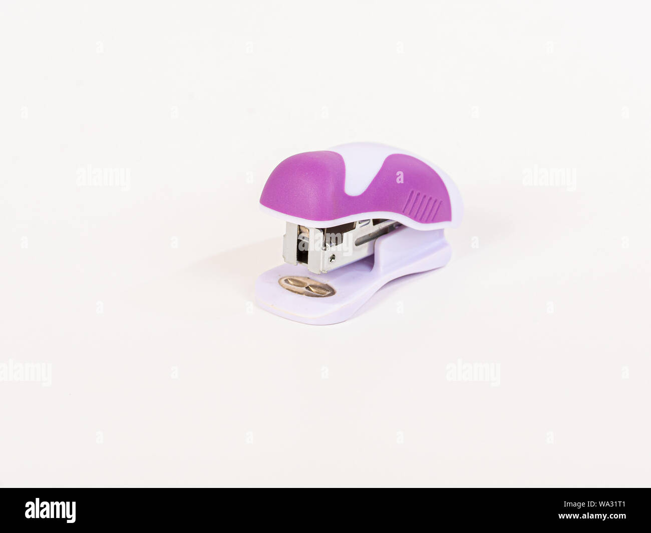 Small, pink stapler with a rounded design on white background. Stock Photo