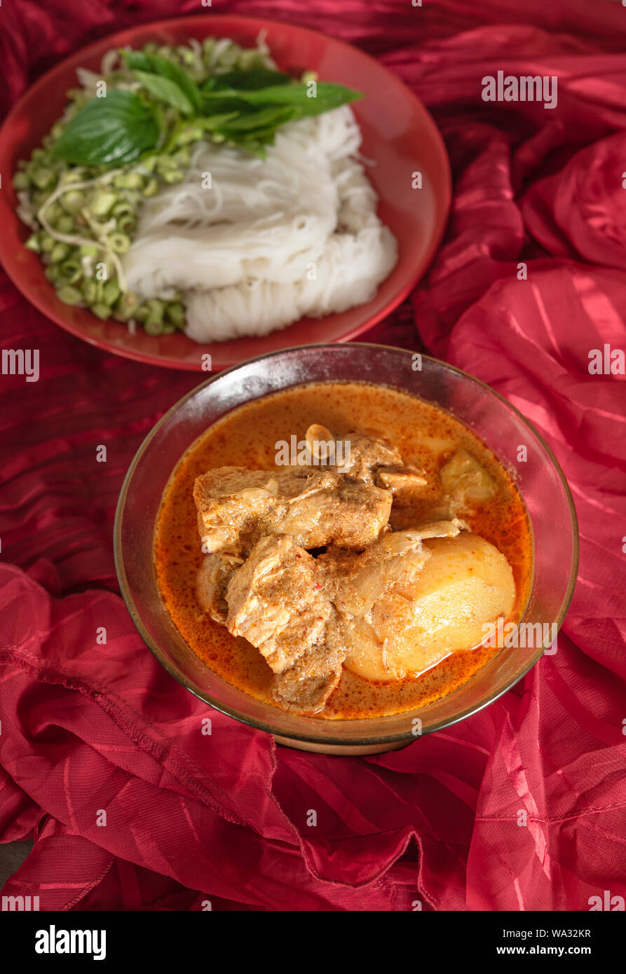 Massaman pork curry served with rice noodles and fresh vegetables