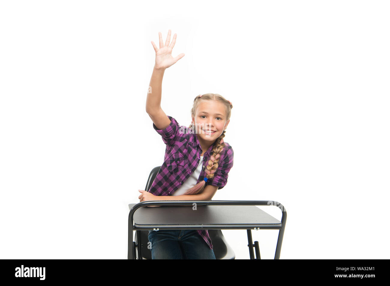She is a bright student. Small girl student raising hand isolated on white. Little student reciting lesson in class. Cute lyceum student sitting at desk. Stock Photo