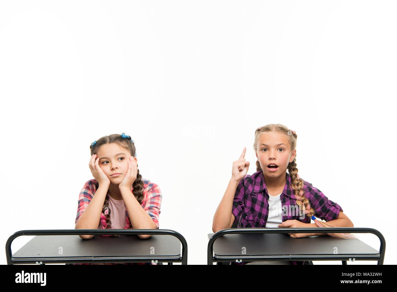 Alternative education idea. Cute children sitting at desks isolated on white. Small girls learning in school of primary education. Little kids getting formal education. Compulsory education is free. Stock Photo