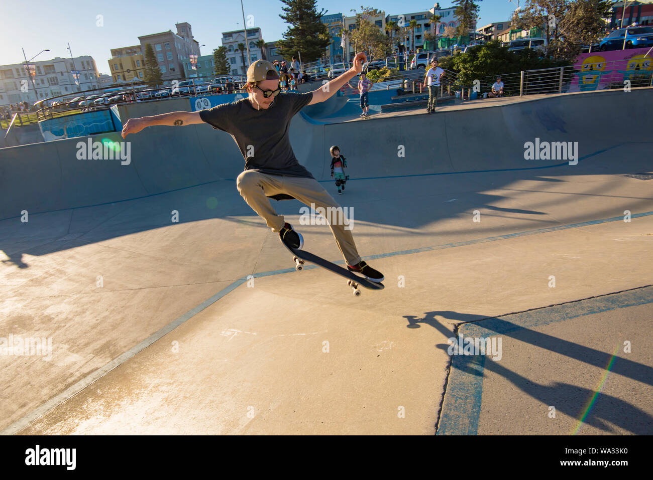In the late summer afternoon sun at the Bondi Beach Skate Park a young male skateboarder gets some air. Stock Photo