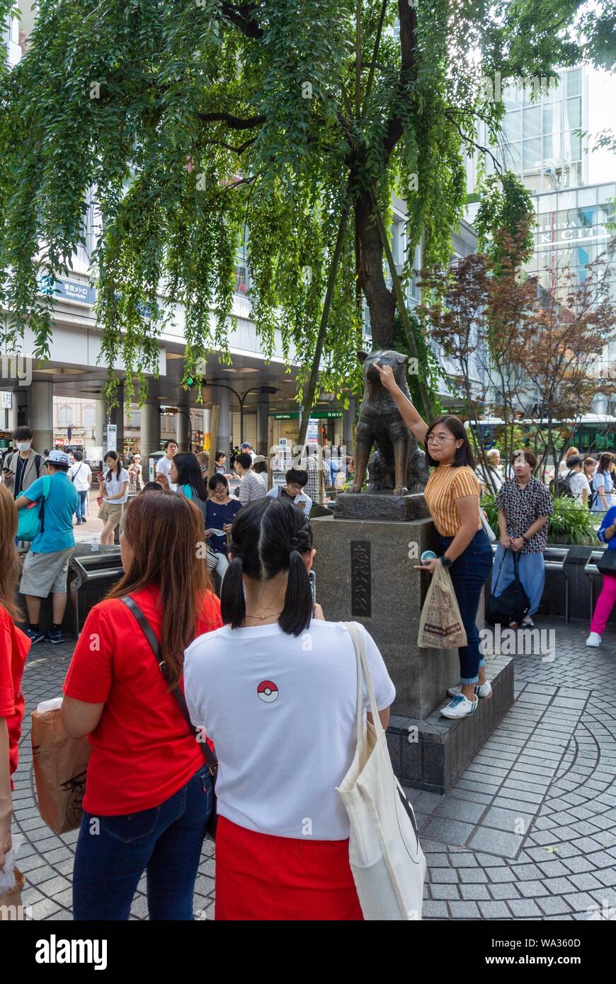 Asian tourists thaking a hoto beside Chuken Hachiko, a famous statue of a faithful dog, shibuya, tokyo, japan Stock Photo