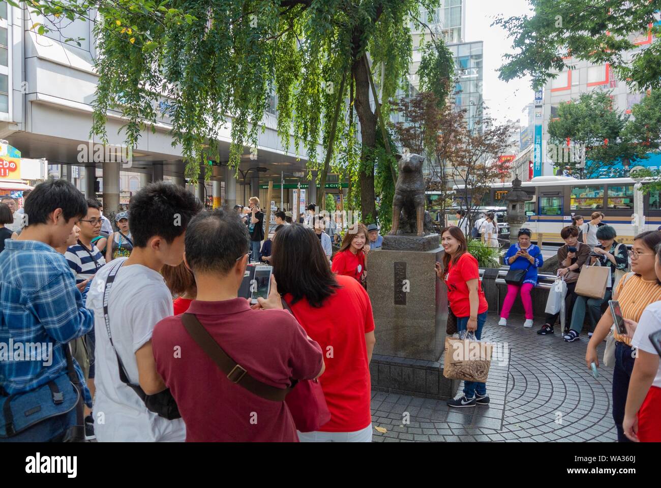Asian tourists thaking a hoto beside Chuken Hachiko, a famous statue of a faithful dog, shibuya, tokyo, japan Stock Photo