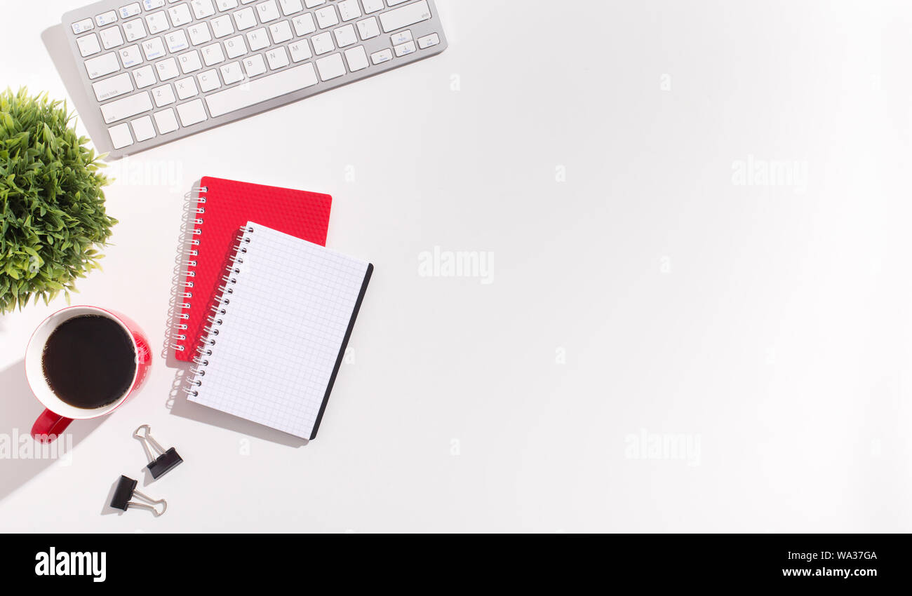 Red and white notebooks and keyboard on white office table Stock Photo