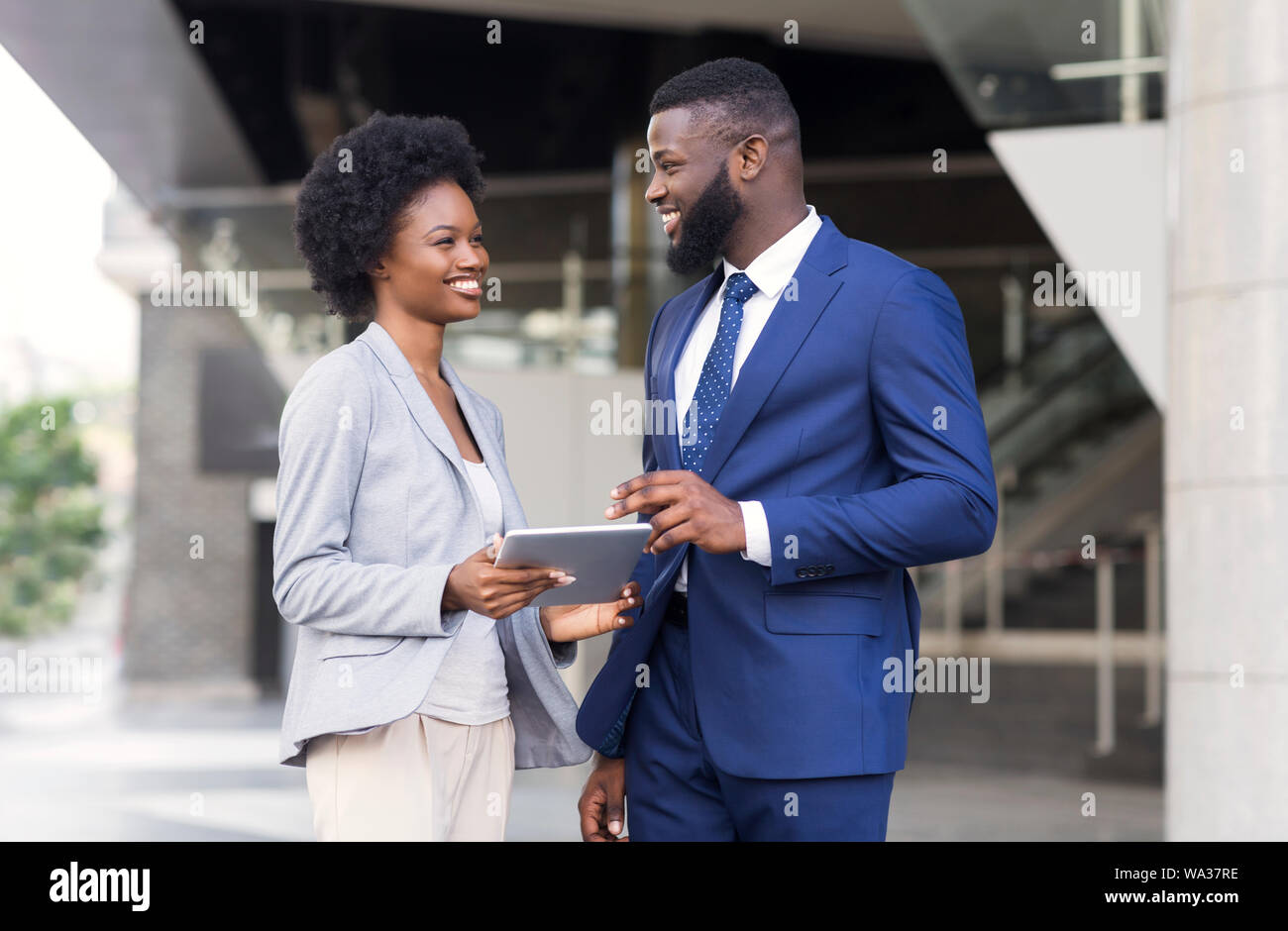 Happy young fellow workers browsing internet on digital tablet outdoors Stock Photo