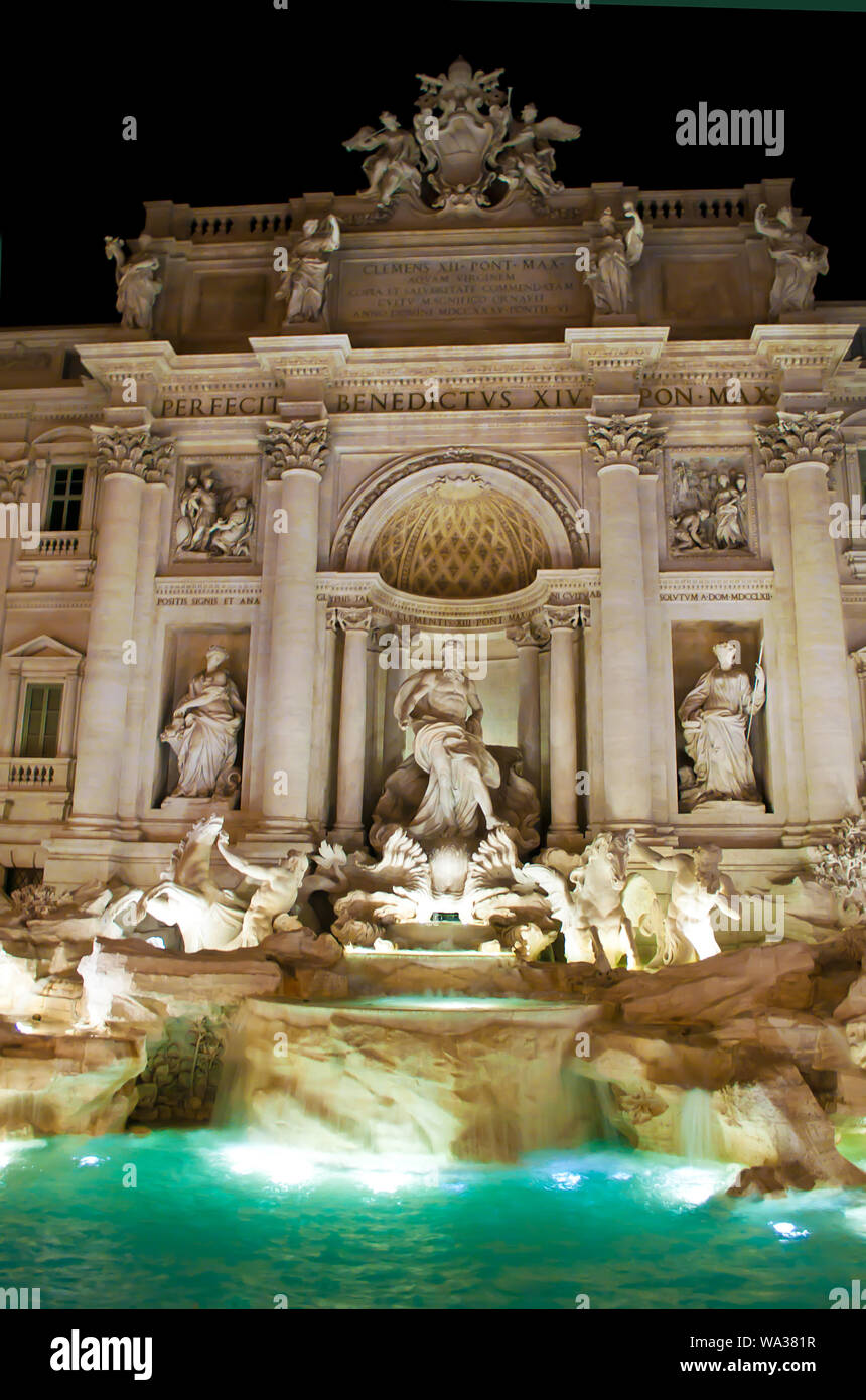 View of the illuminated Fontana di Trevi and green flowing waters at night. Many intricate statues and marble columns Stock Photo