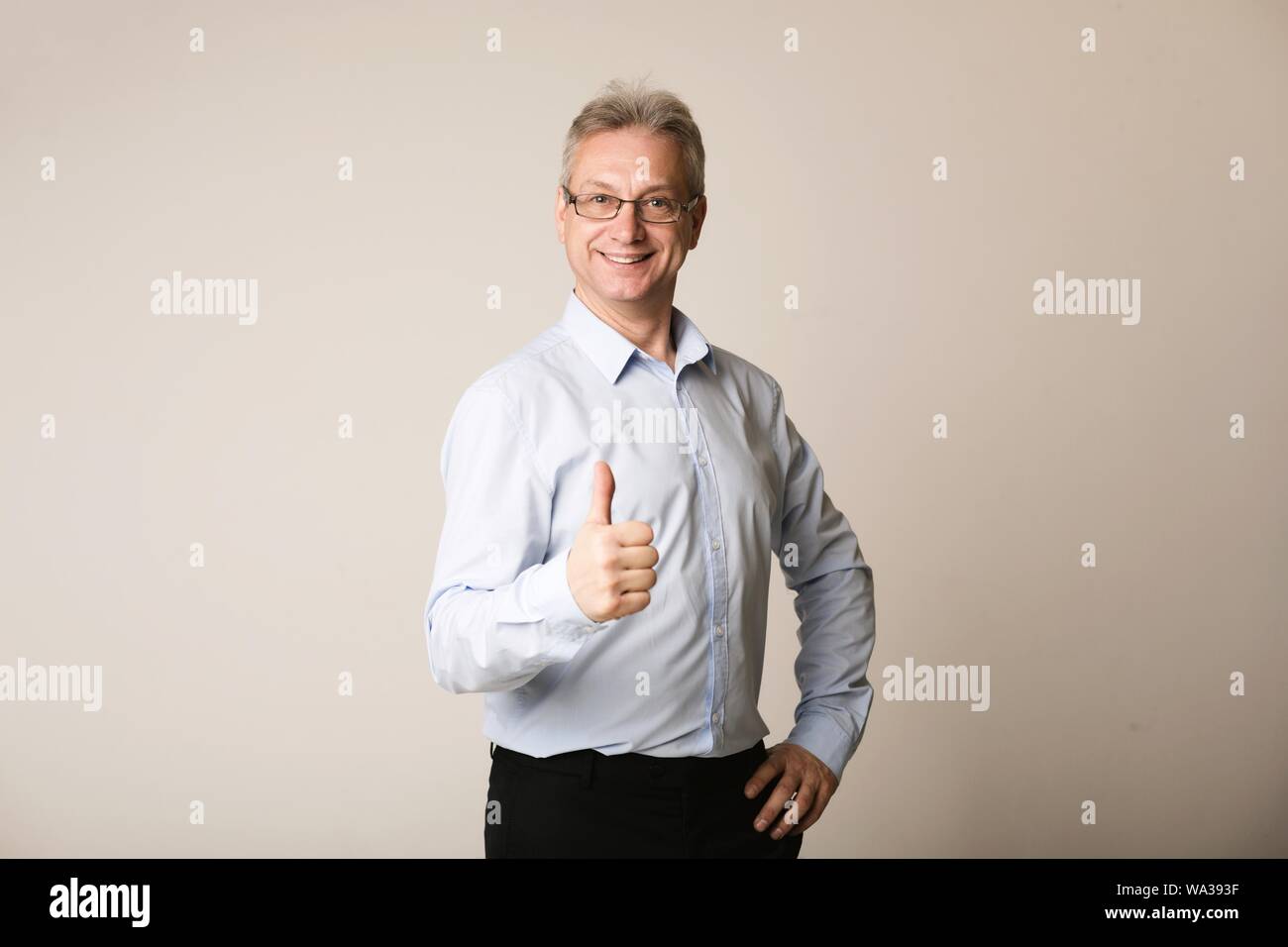 Mature businessman showing thumb up, smiling to camera Stock Photo