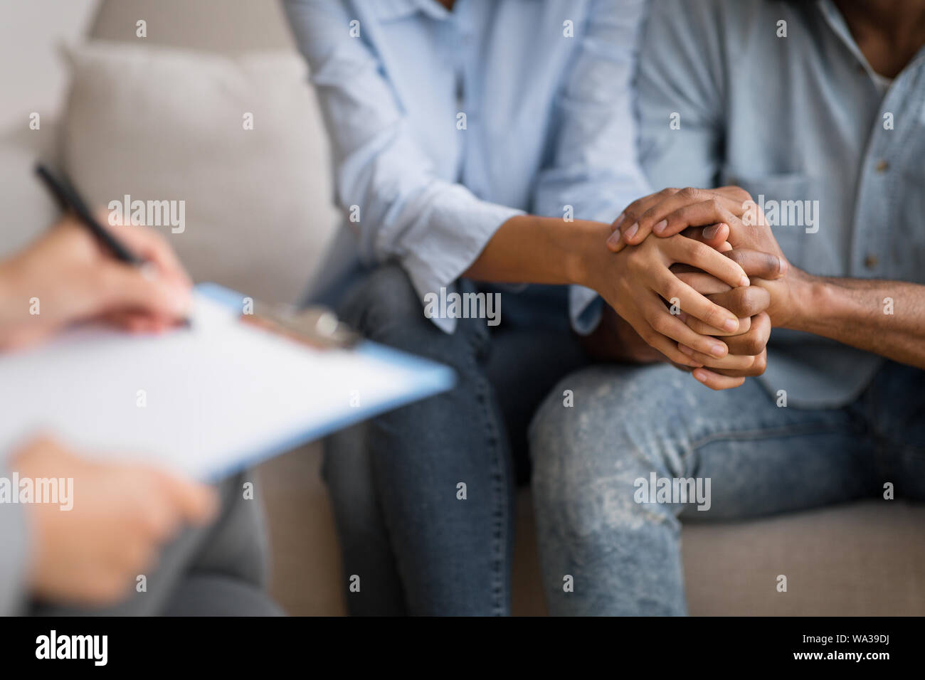 Black Husband And Wife Holding Hands At Marital Psychologist's Office Stock Photo