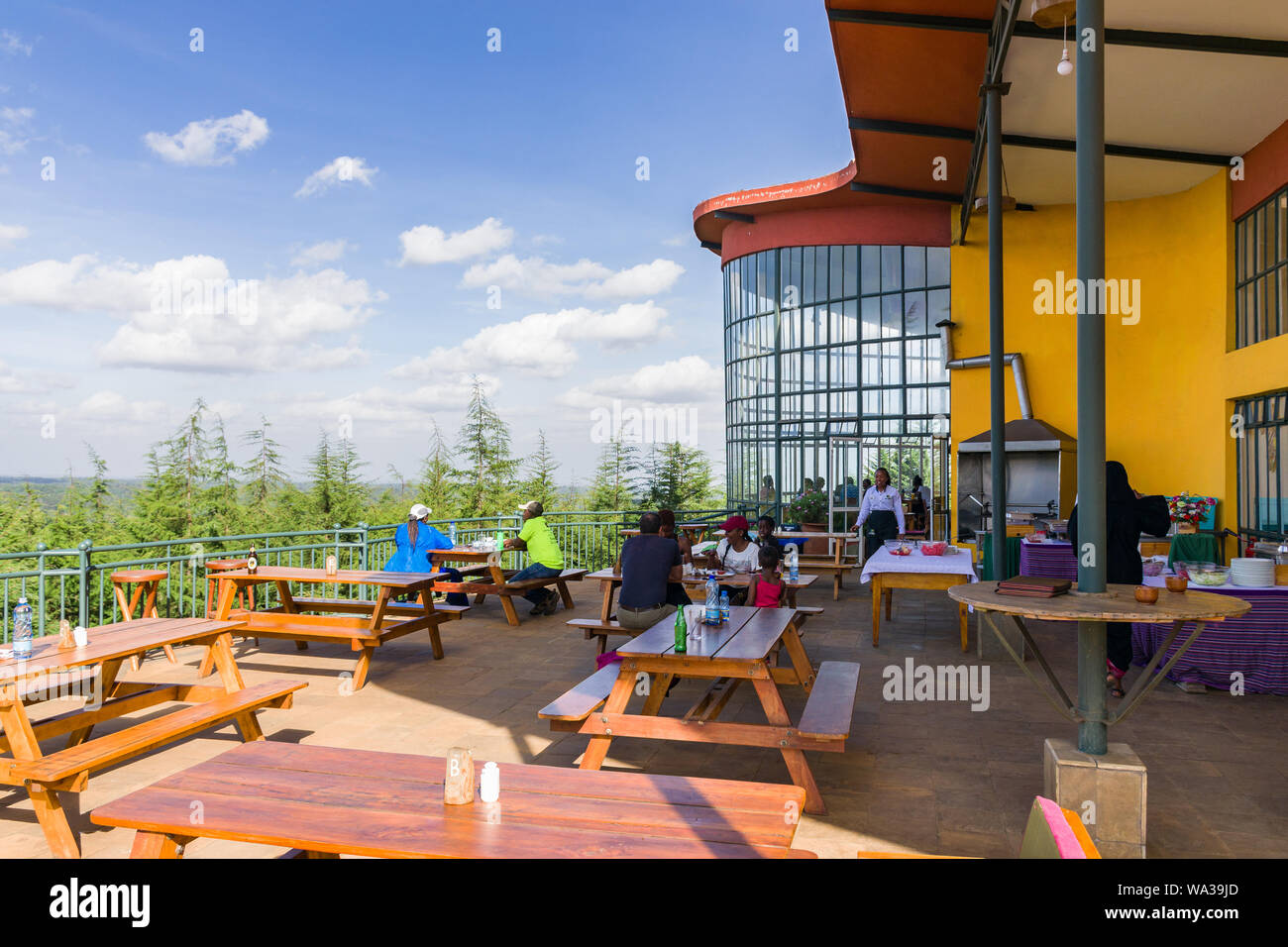 Exterior seating area of The Forest main building with people sat enjoying the view, Kimende, Kenya Stock Photo