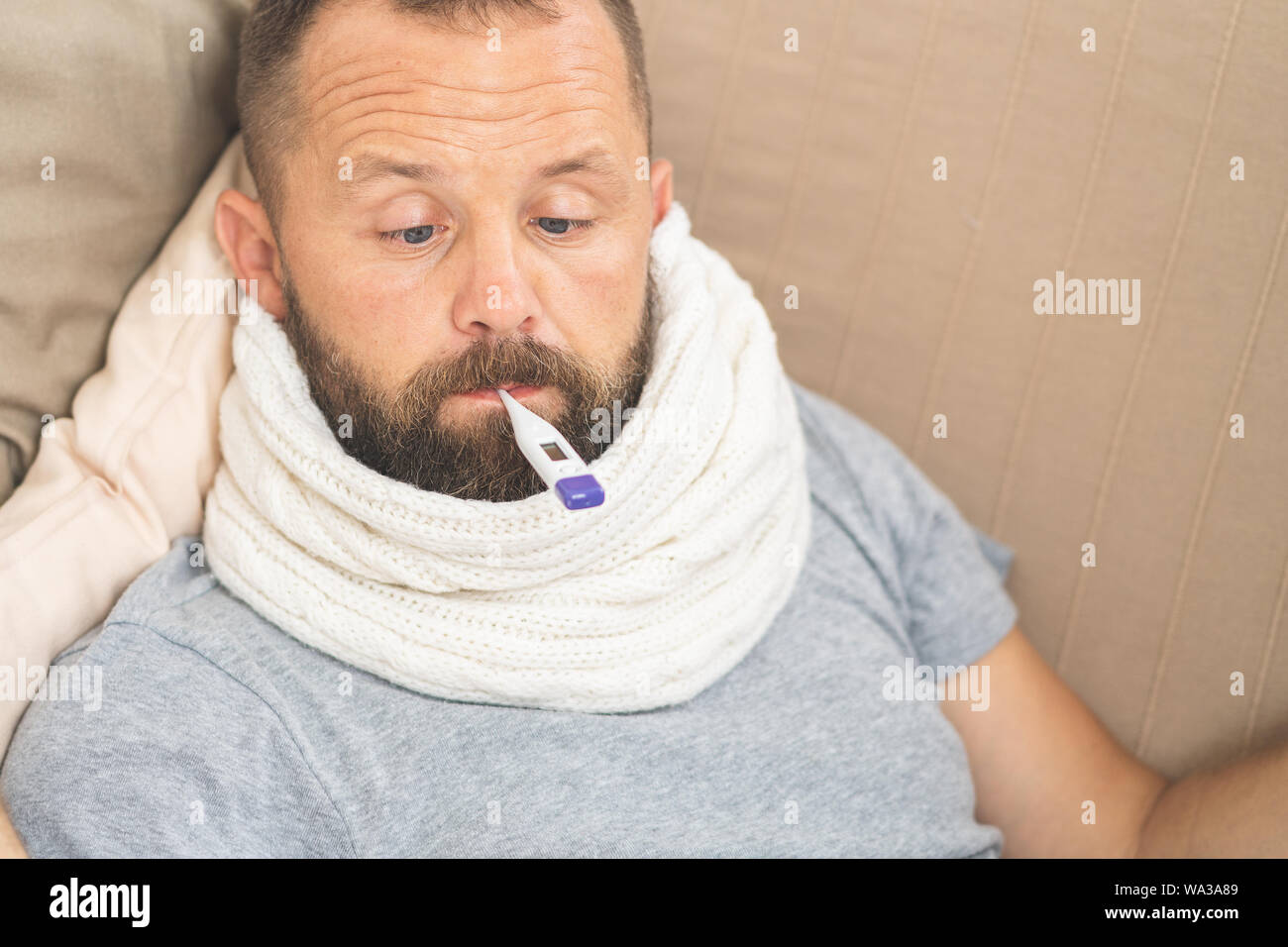 Man feeling bad lying in bed and looking the thermometer , main focus