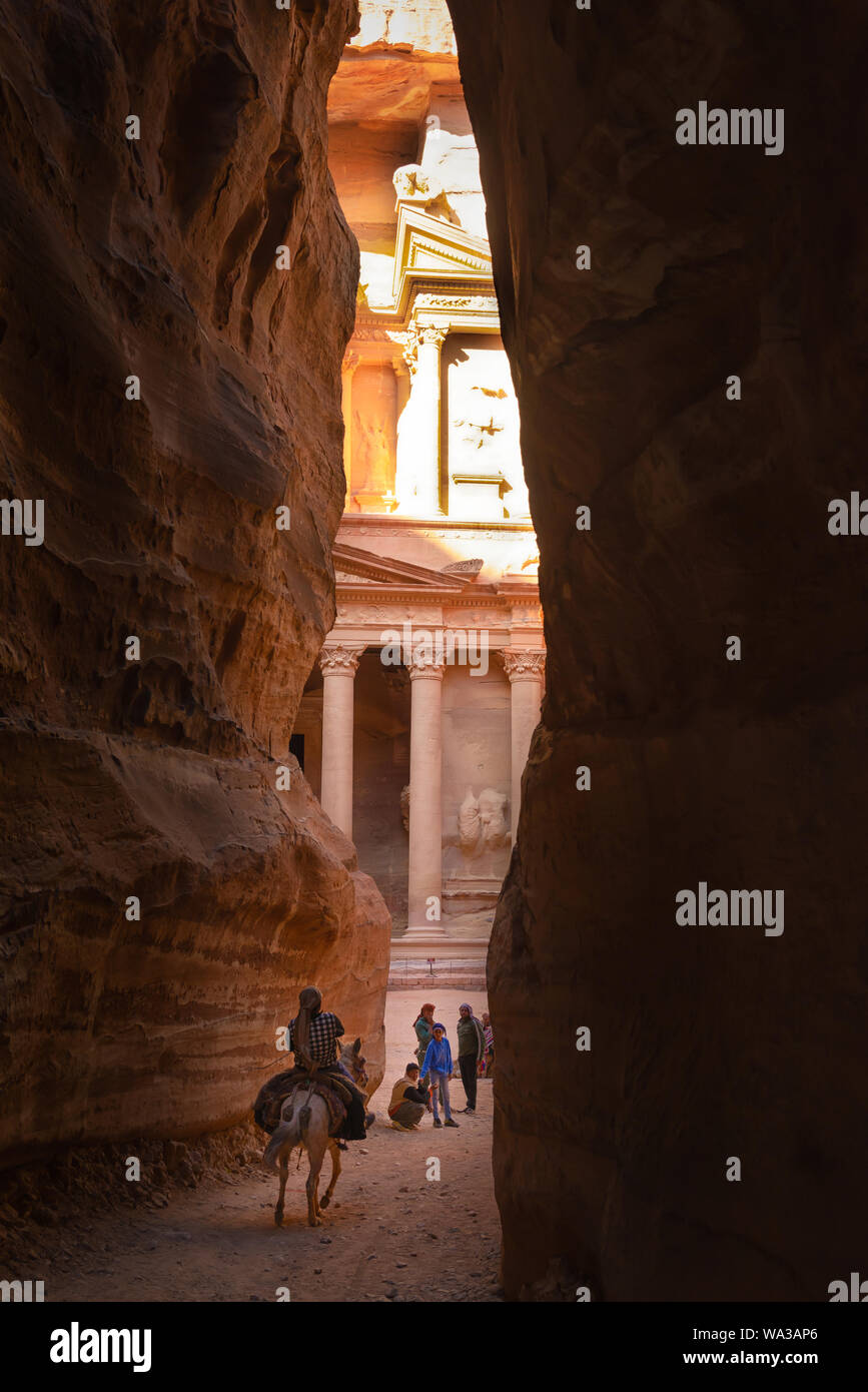 Petra, Jordan - April 06, 2015: Bedouin riding a mule at the end of the Siq, coming out in front of the Treasury, one of the most elaborate temples Stock Photo