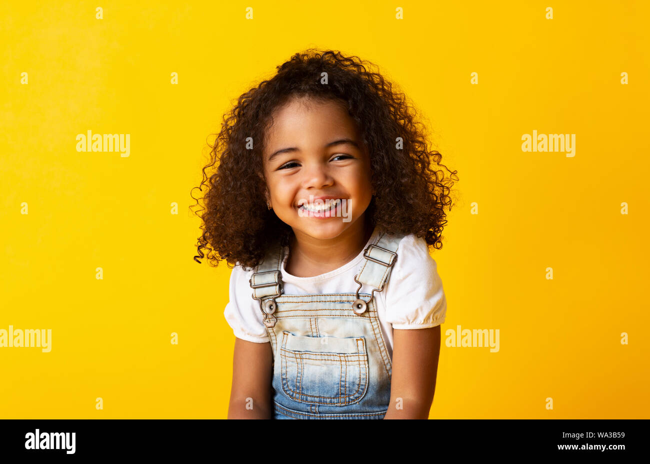 Happy smiling african-american child girl, yellow background Stock Photo