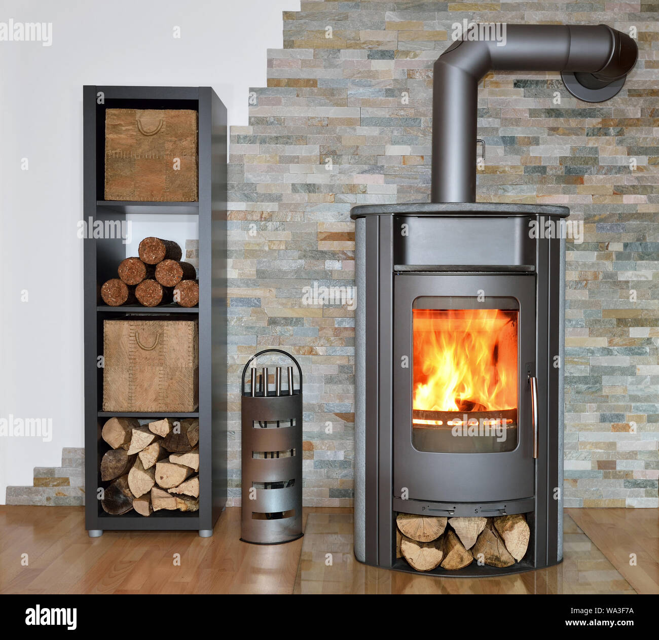 wood fired stove with fire-wood, fire-irons, and briquettes from bark Stock Photo