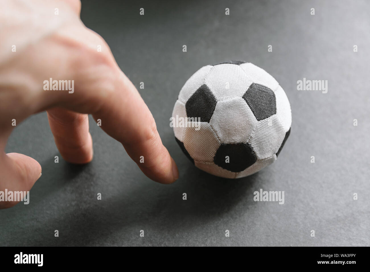 Hand kicks a soccer ball - conceptual photo. Stock Photo