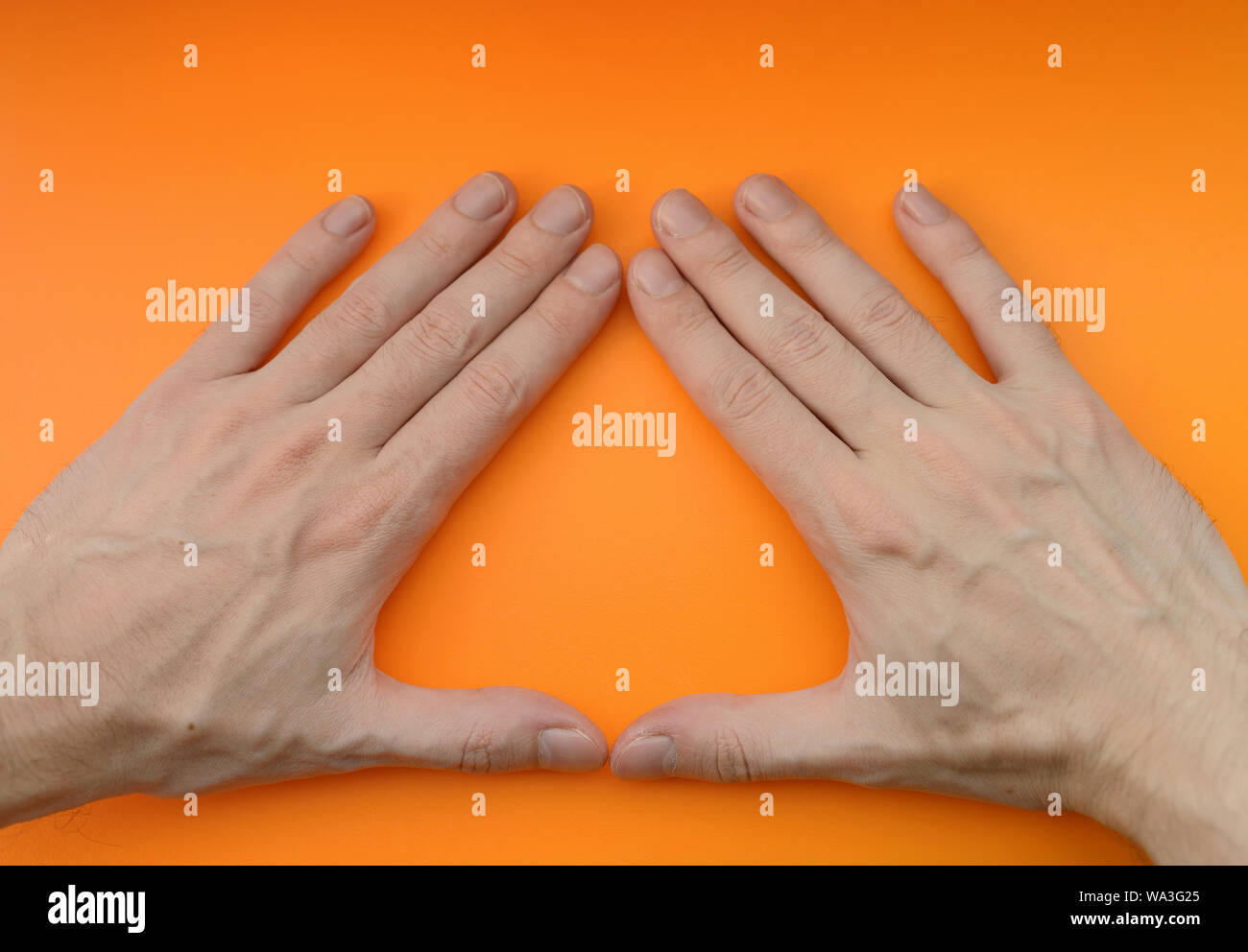 Hand sign triangle on orange background. Stock Photo