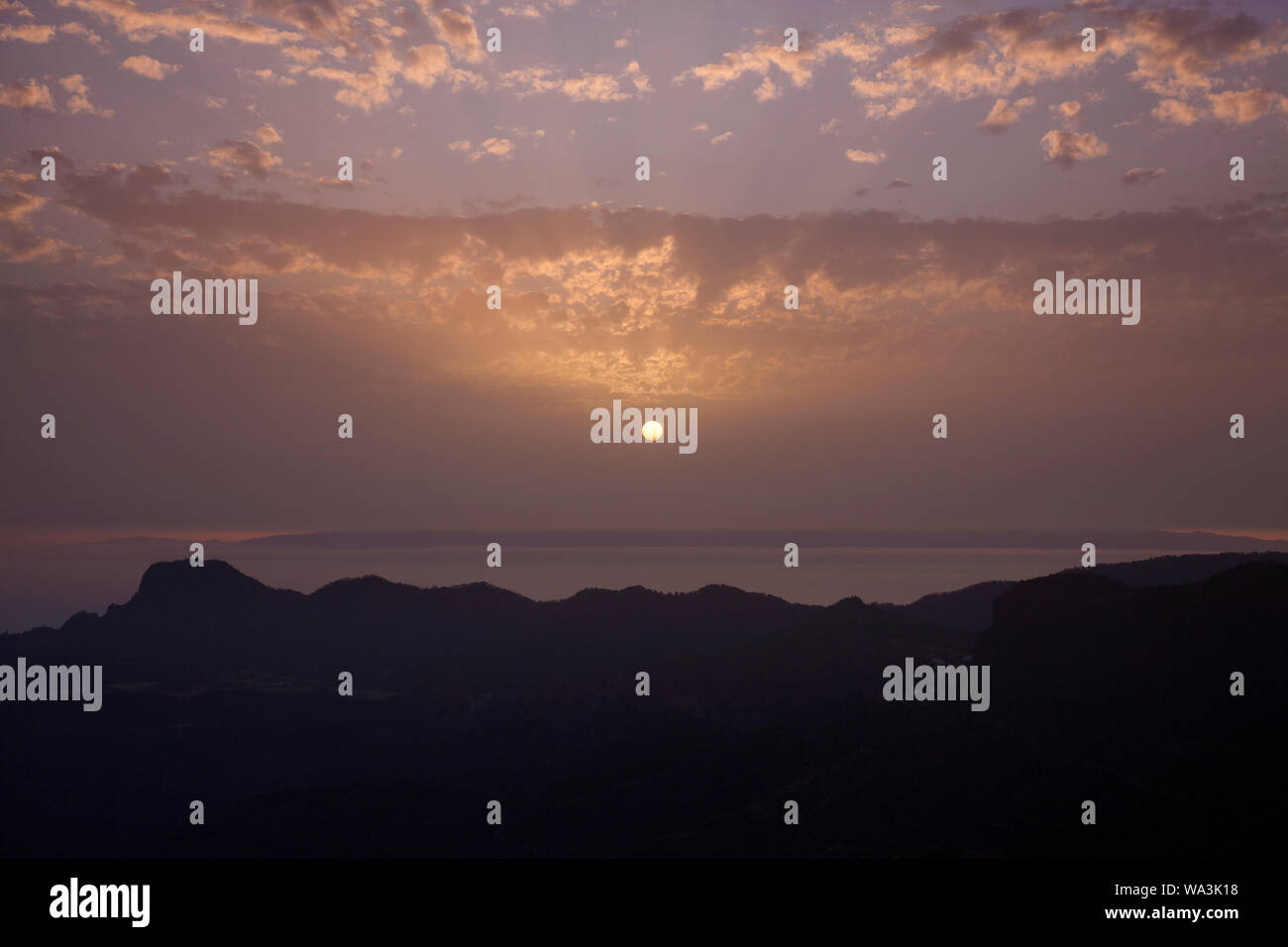 Gran Canaria, August, calima, dust haze from Sahara hanging over Caldera de Tejeda, spooky sunset, only lower level of Tenerife visible over Altavista Stock Photo