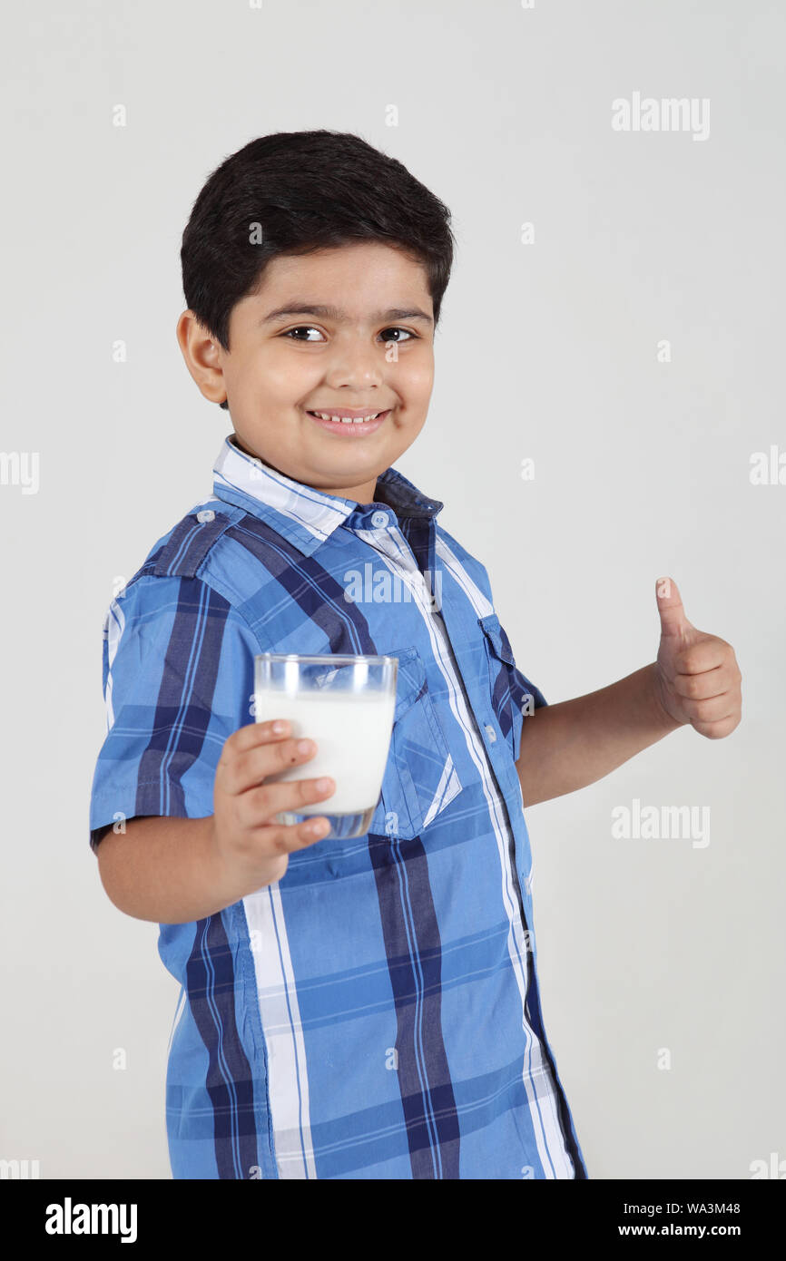 Boy holding a glass of milk and making thumbs up sign Stock Photo