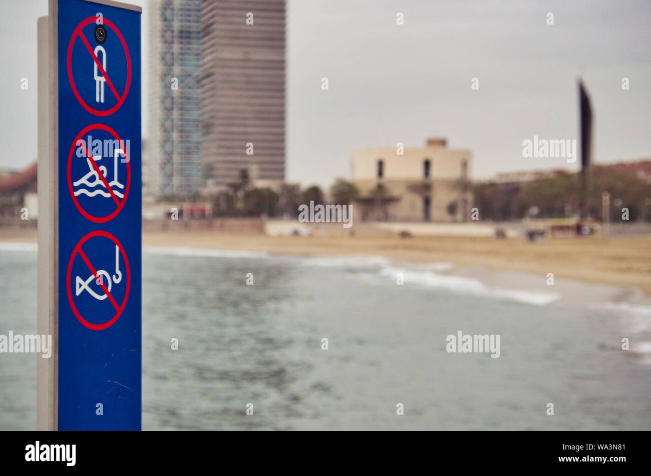 Warning signs in the 'Nova Icaria' beach in the coast of Barcelona with the 'Port Olimpic' buildings at the background Stock Photo