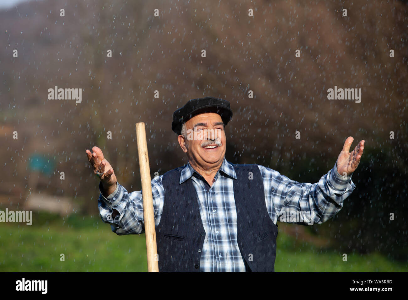 Farmer in the rain ,arms open and happy Stock Photo