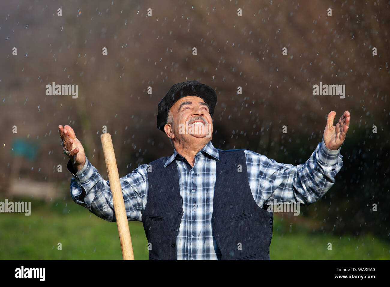 Farmer in the rain ,arms open and happy Stock Photo