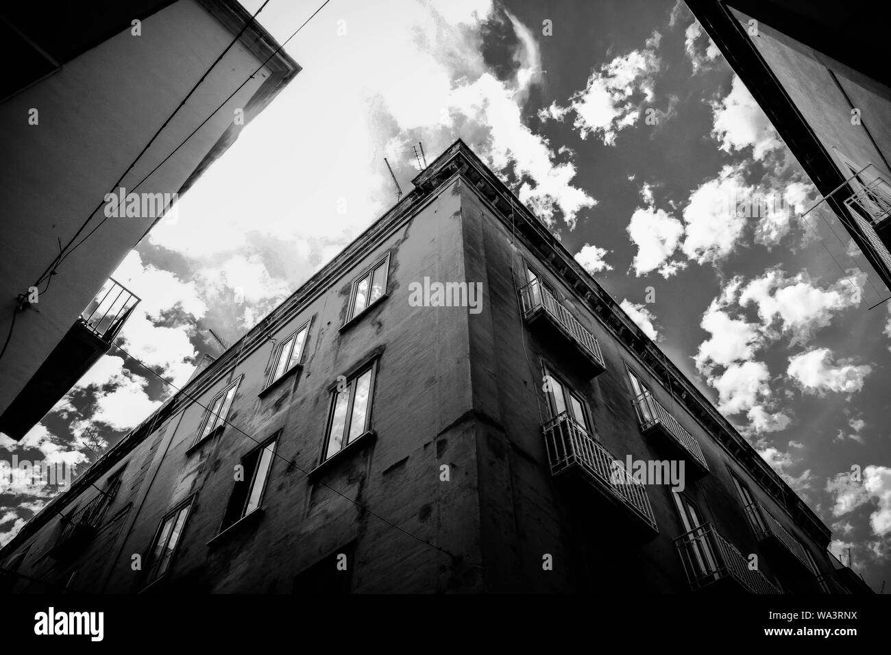 Low angle shot of a building with windows under a cloudy sky in black ...