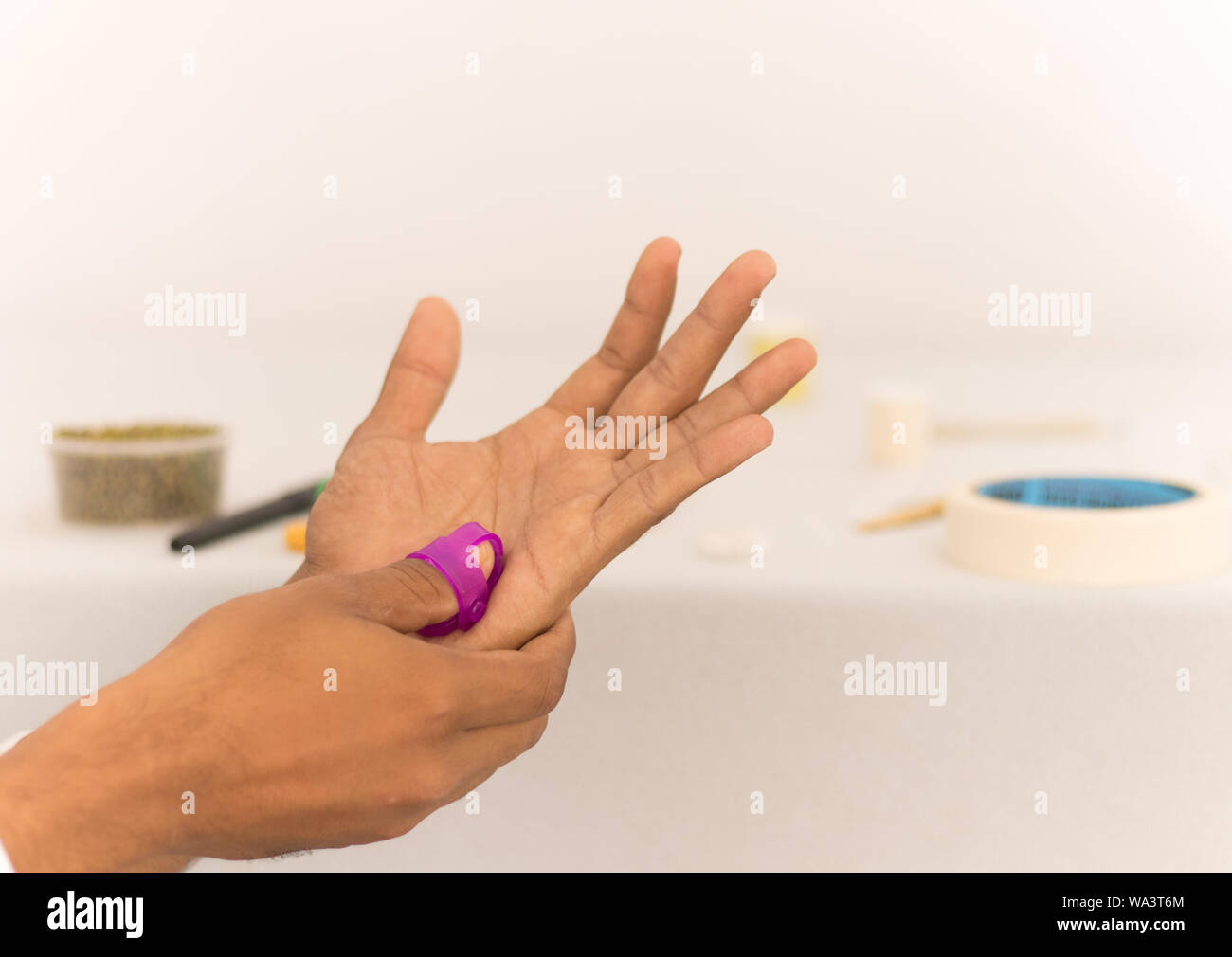 Sujok or acupressure therapy, applying pressure to the fingers with Sujok massager on isolated backgroud Stock Photo