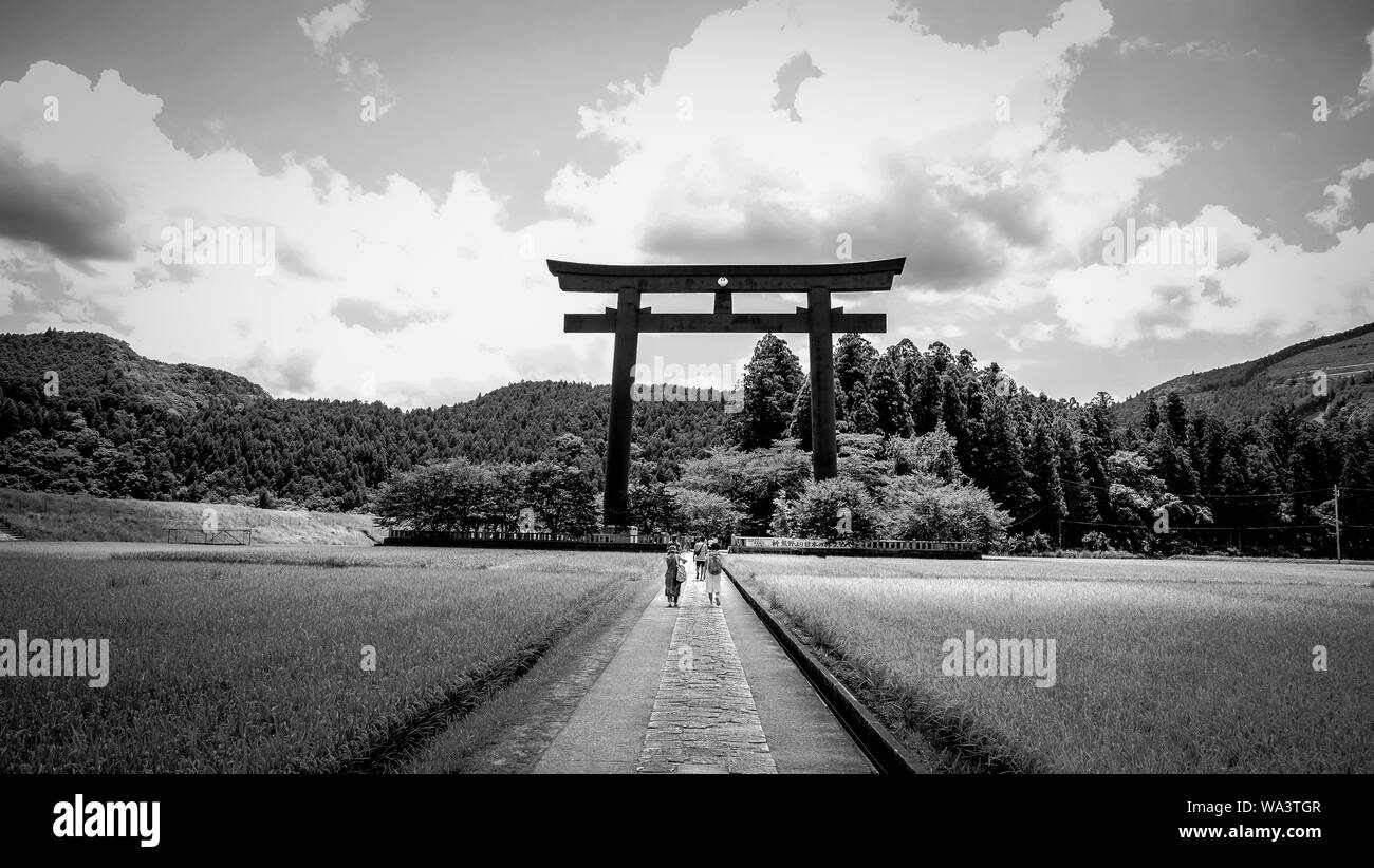 Beautiful shot of people walking on a pathway towards the Tori Gate in black and white Stock Photo