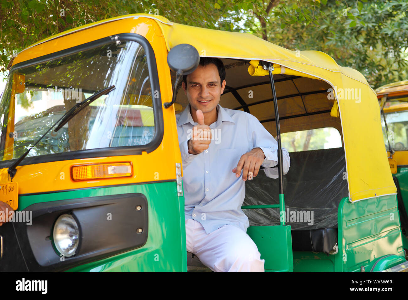 Auto driver sitting in an auto rickshaw and showing thumbs up sign Stock Photo
