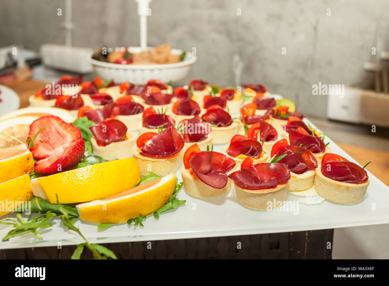 Prosciutto and rosemary with melted cheddar cheese Canape - single bite serving - arranged party finger food - cold buffet Stock Photo