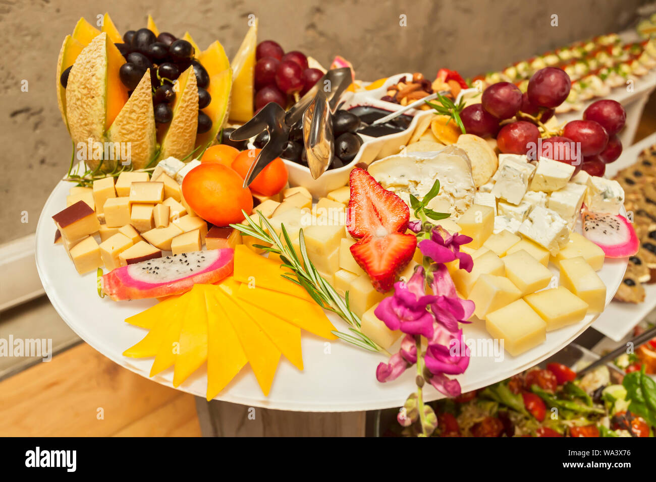 Fresh fruit strawberries, grapes and melon on skewers with various cheese bites - Single bite serving - arranged party finger food Stock Photo