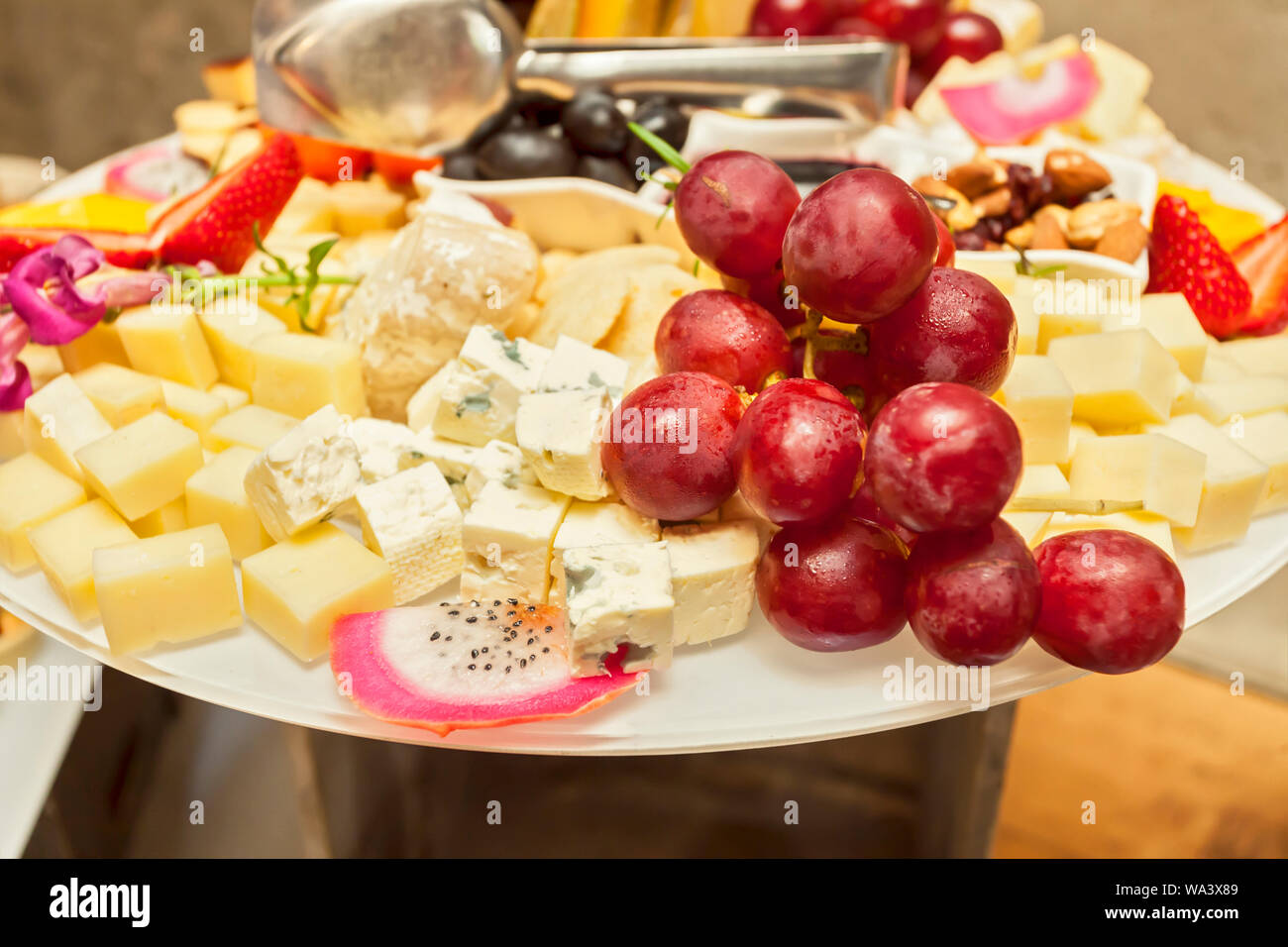 Fresh fruit strawberries, grapes and pitaya on skewers with various cheese bites - Single bite serving - arranged party finger food Stock Photo