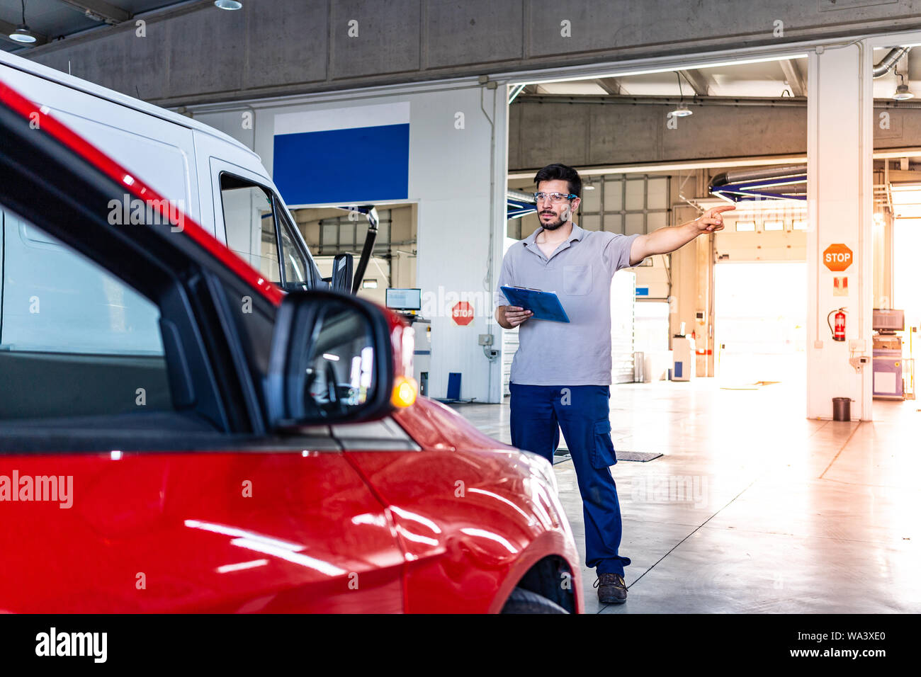 Technician with safety glasses checking the turn lights of a car during a vehicle inspection