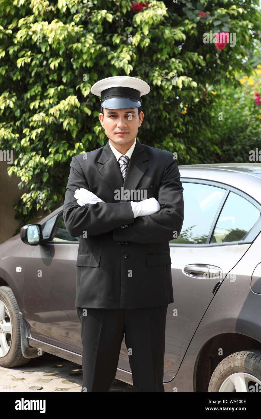 Chauffeur standing with his arms crossed at a car Stock Photo